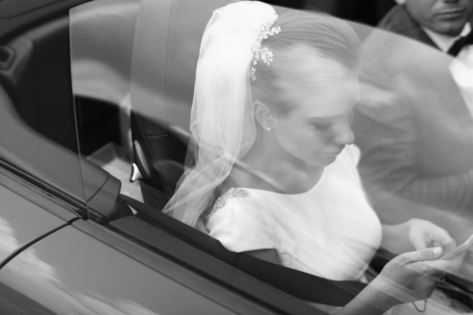 No carro, uma noiva aguardando o momento de entrar na cerimônia, refletindo momentos de expectativa e calmaria antes do casamento.