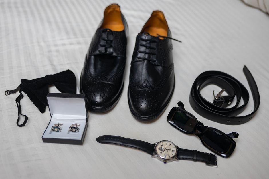 Conjunto de acessórios masculinos formais, incluindo sapatos, relógio, cinto, óculos de sol, abotoaduras e gravata, ideal para um look profissional ou passeio elegante.