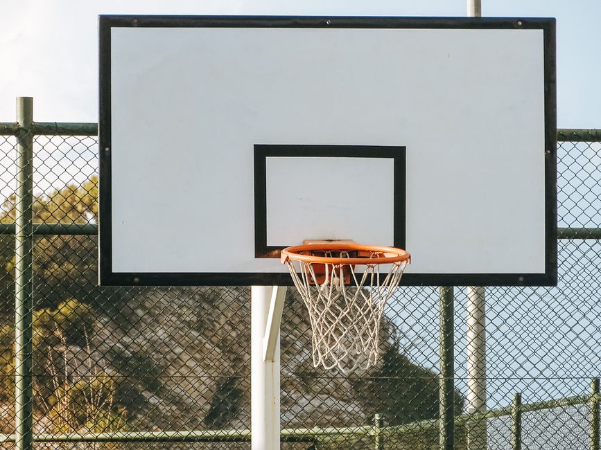 Quadra de basquete ao ar livre com tabela de aros e rede, em ambiente externo.