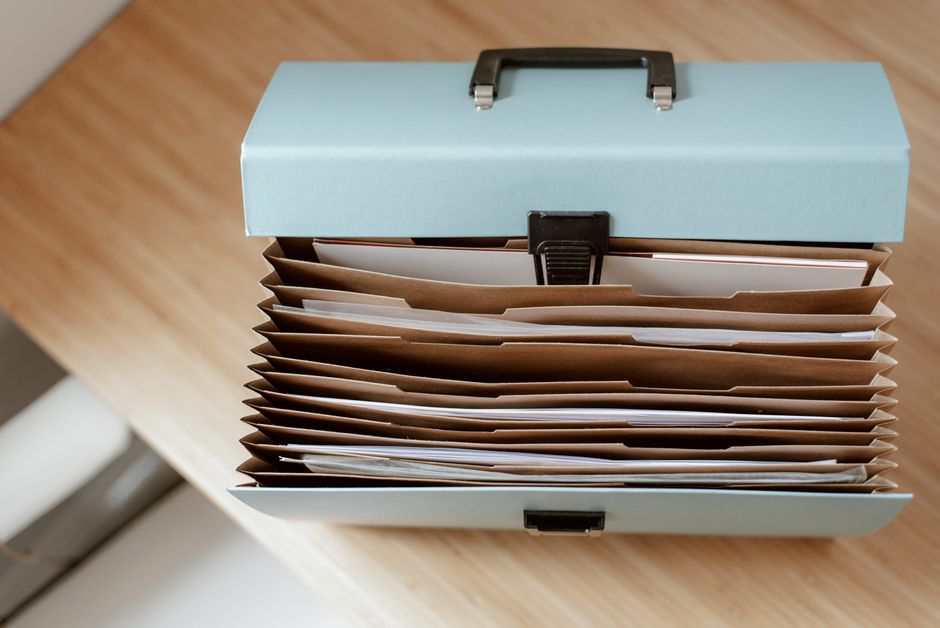 Imagem de uma caixa organizadora com várias pastas de arquivo, ideal para artigos sobre organização de documentos e gestão de arquivos.
