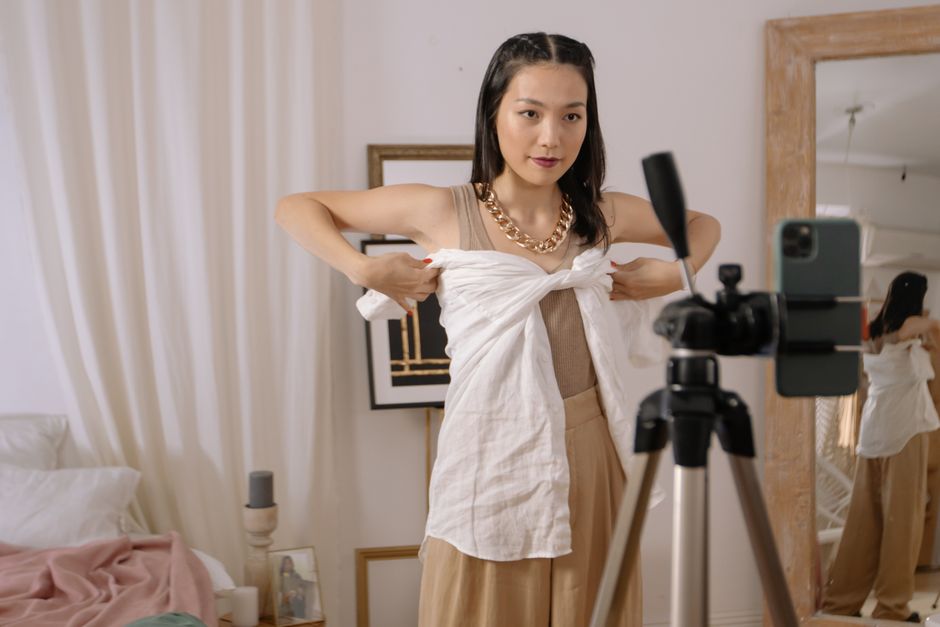 Mulher se preparando para gravar um vídeo de moda ou conteúdo de estilo em um ambiente doméstico bem decorado.