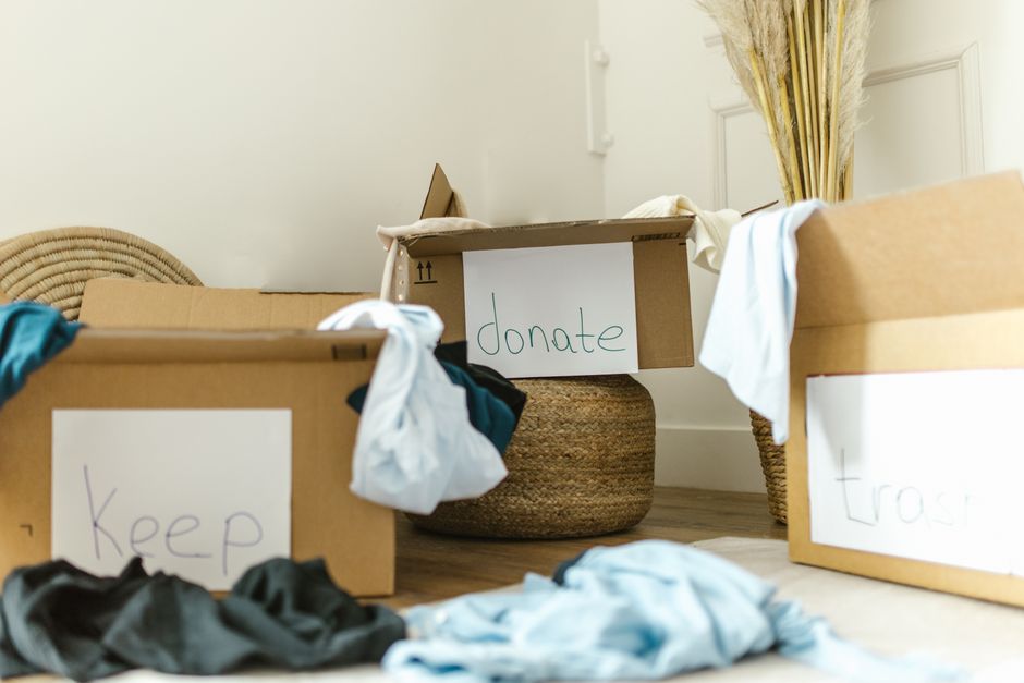 Imagem de caixas de doações e roupas usadas, ilustrando temas de solidariedade e arrecadação de roupas para doação.