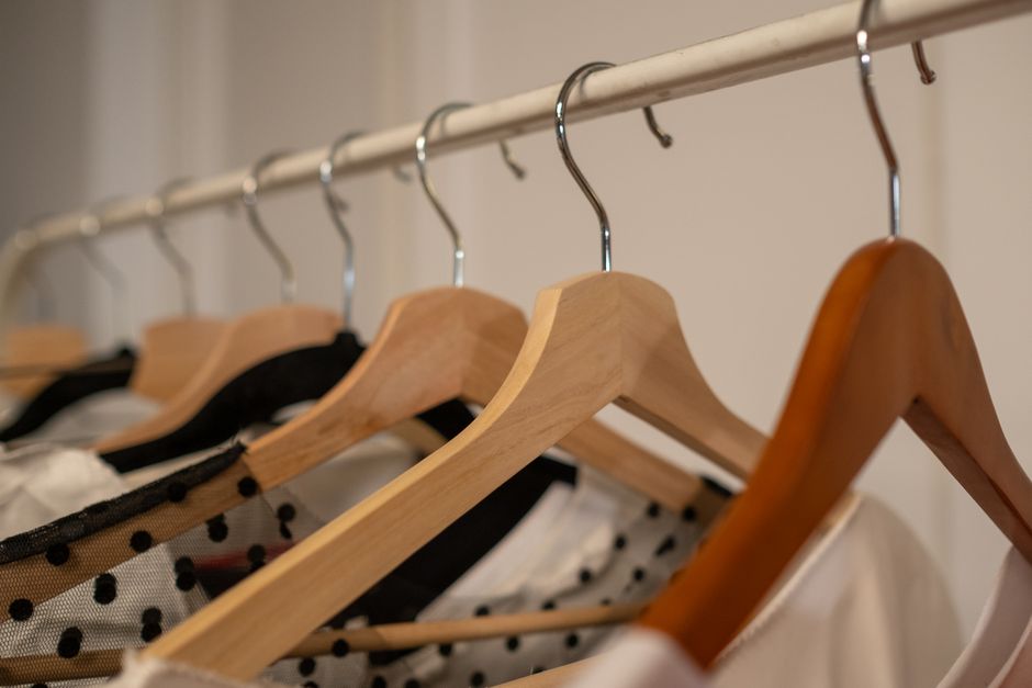 Imagem de cabides com roupas em um armário, destacando organização e moda feminina para artigos sobre styling ou organização de closet.