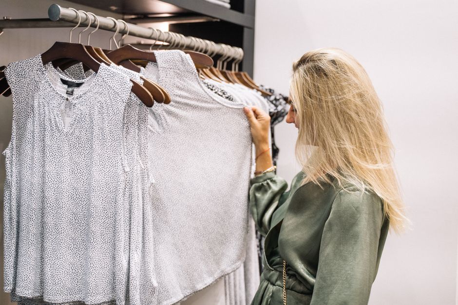 Mulher escolhendo roupas em uma loja de moda feminina, refletindo sobre estilo e gosto pessoal.