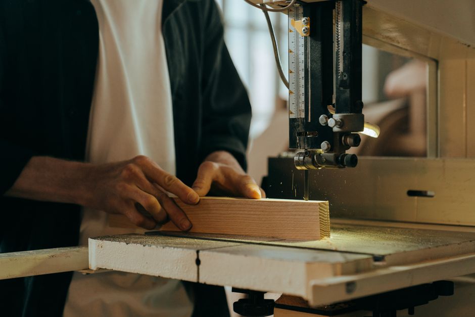 Pessoa operando uma máquina de serrar madeira, ilustrando o processo de marcenaria e fabricação artesanal.