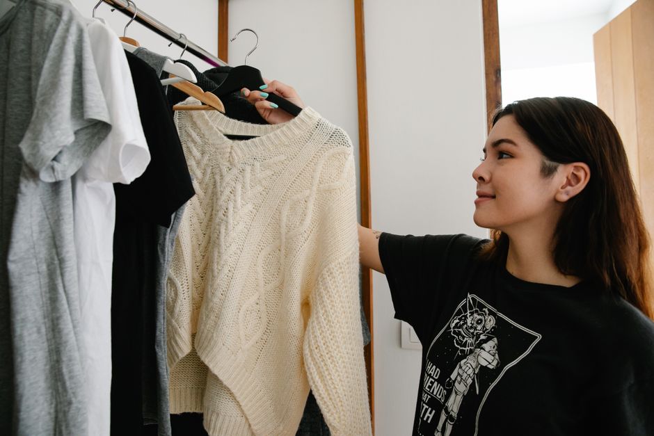 Mulher escolhendo roupas em um closet, ilustrando temas de moda, estilo ou organização de guarda-roupa.