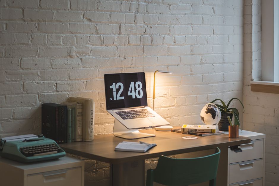 Imagem de um espaço de trabalho moderno com computador, livros e elementos decorativos, ideal para artigos sobre produtividade e organização no home office.