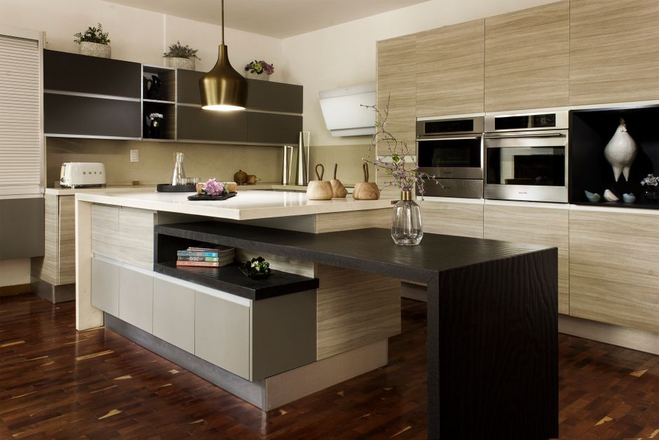 Imagem de uma cozinha moderna com móveis de madeira clara, eletrodomésticos embutidos e uma ilha central, ideal para artigos sobre design de cozinhas e decoração residencial.