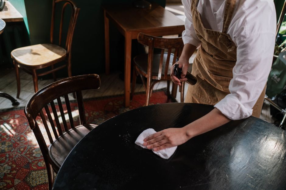 Pessoa limpando uma mesa de restaurante, destacando a rotina de manutenção e higiene no ambiente de alimentação.