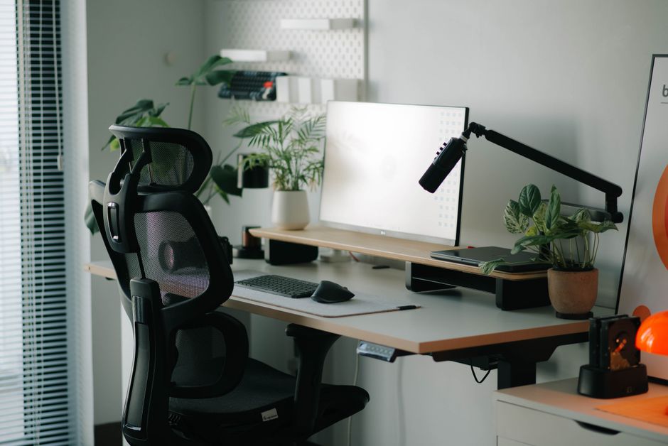 Imagem de um ambiente de trabalho moderno com mesa de escritório, computador, plantas e iluminação adequada, ideal para artigos sobre home office ou produtividade.