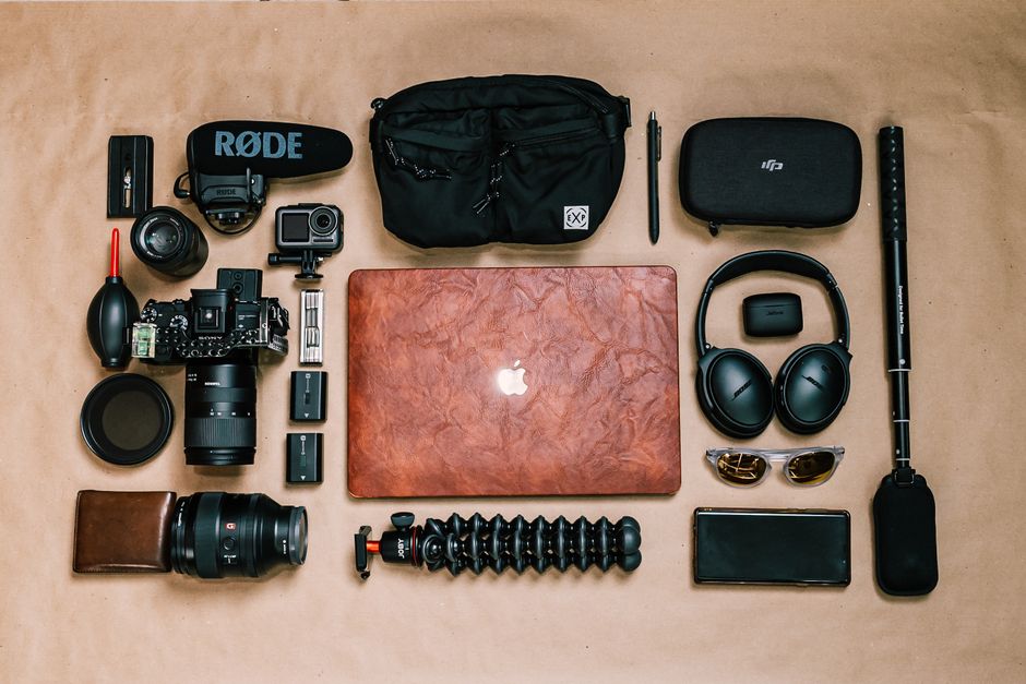 Conjunto de equipamentos tecnológicos e de fotografia organizados sobre uma superfície, sugerindo preparação para produção de conteúdo ou trabalho criativo.