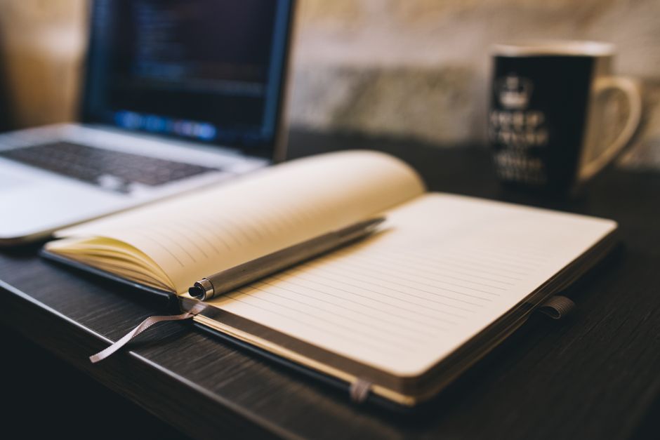 Imagem de um ambiente de trabalho com um caderno aberto, laptop e uma caneta, ideal para temas relacionados a produtividade, organização ou planejamento pessoal e profissional.
