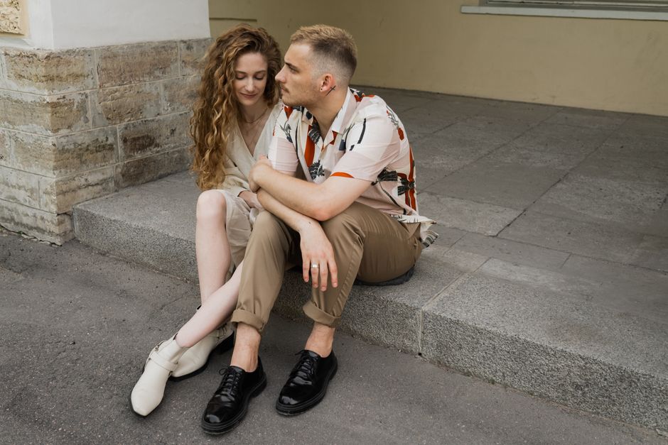 Casal sentado na calçada, compartilhando um momento de conexão e intimidade em um ambiente urbano aconchegante.