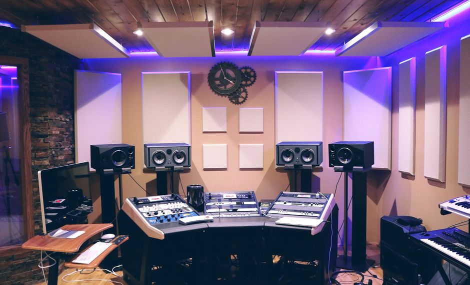 Estúdio de gravação musical equipado com instrumentos, monitores e iluminação moderna para produção de áudio profissional.