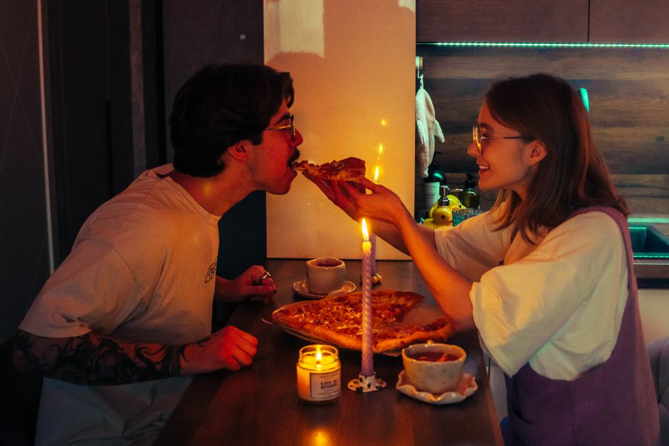 Dupla de amigos compartilhando uma pizza em clima de celebração em um ambiente acolhedor e moderno.
