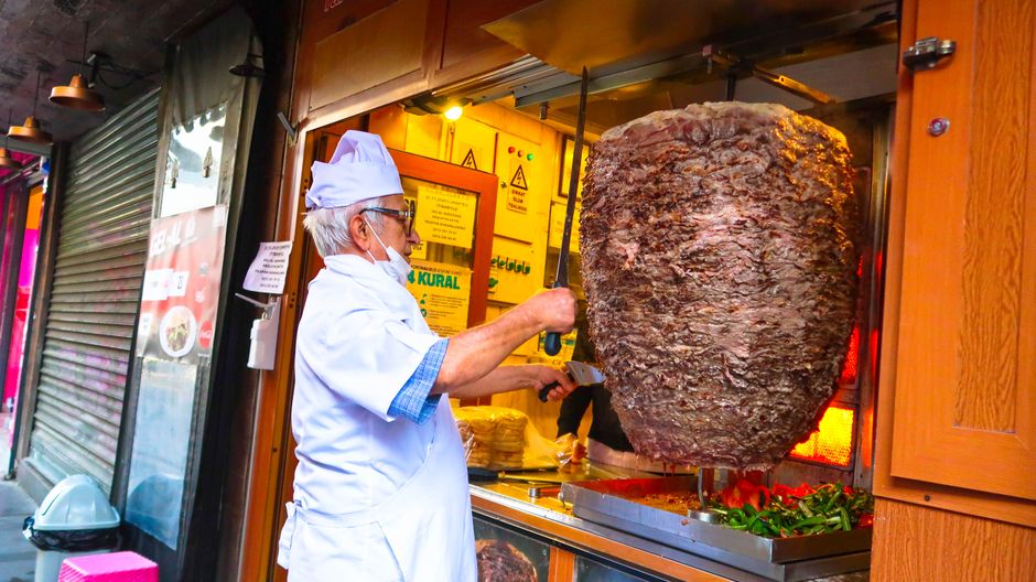 Homem preparando carne assada em um food truck com foco na gastronomia tradicional turca.