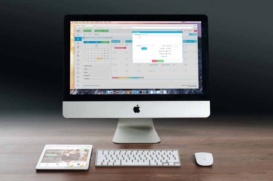 Imagem de um setup de trabalho com um computador de mesa, teclado, mouse e um tablet, focando no ambiente de escritório digital e produtividade.
