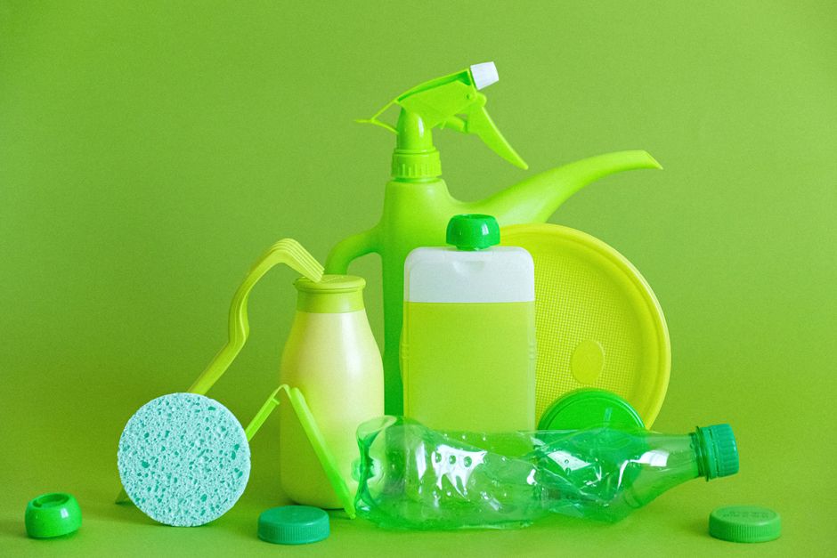 Imagem de produtos de limpeza ecológicos em recipiente de cores vibrantes, destacando a preocupação com sustentabilidade.