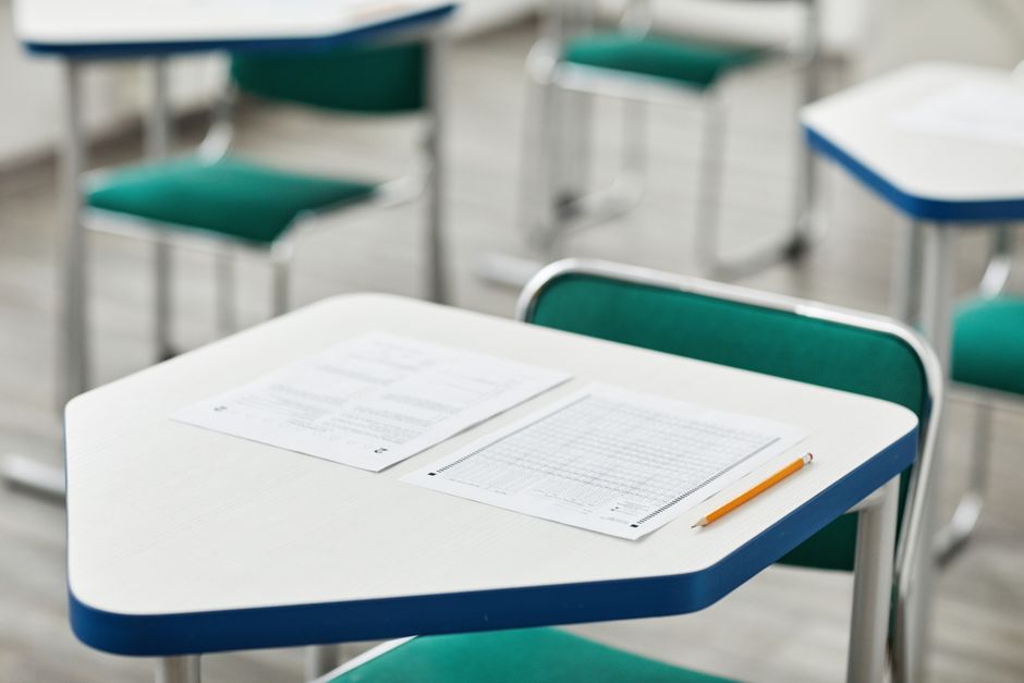Imagem de uma sala de aula vazia com mesas e cadeiras organizadas, ideal para ilustrar temas relacionados à educação, ensino ou formação acadêmica.