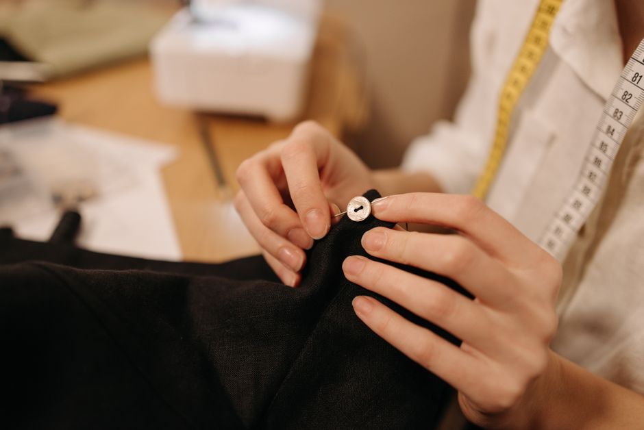 Costureira ajustando uma roupa com atenção aos detalhes, representando artesanato e precisão na confecção de roupas.