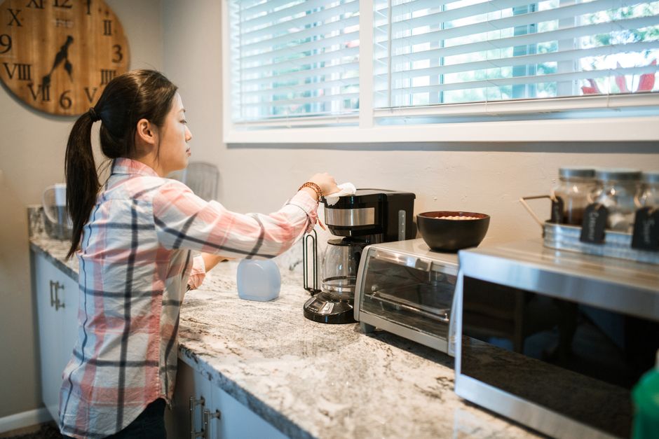 Mulher preparando café na cozinha, simbolizando rotina matinal ou organização doméstica.