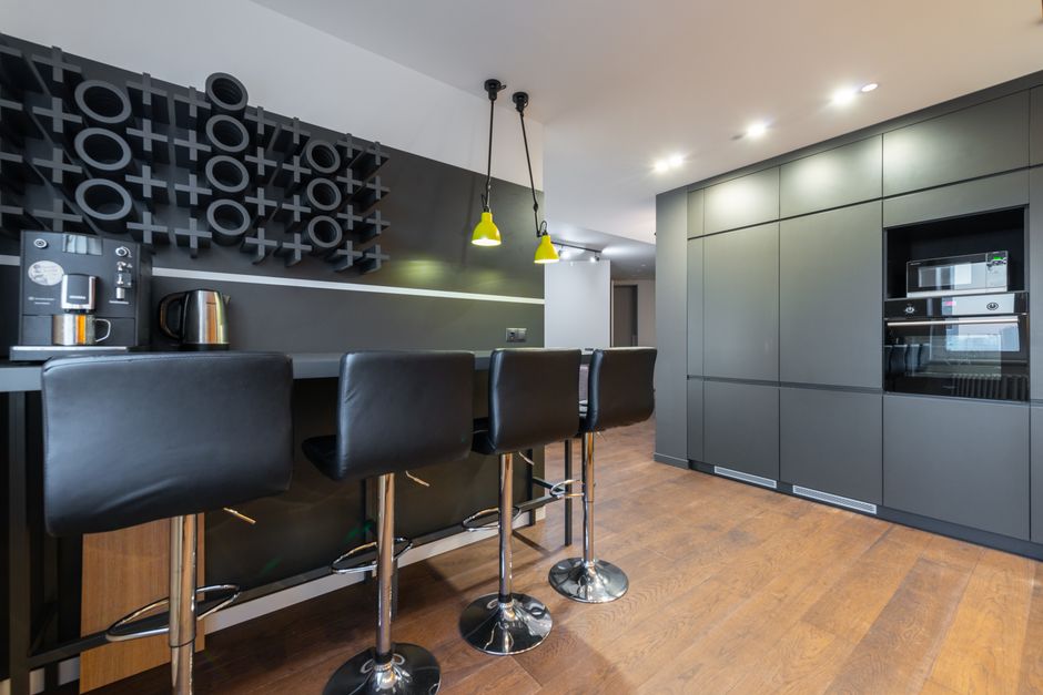 Imagem de uma cozinha moderna com armários cinza, bancada clean e iluminação elegante, perfeito para ambientes de convivência e lazer em residências contemporâneas.