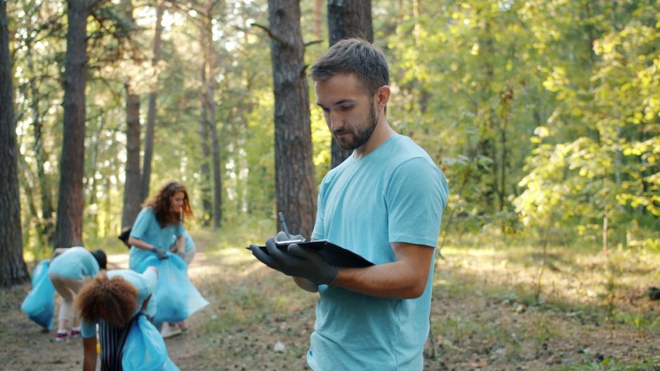 Jovens realizando uma limpeza ambiental em meio à natureza no parque, com foco na preservação do ambiente.