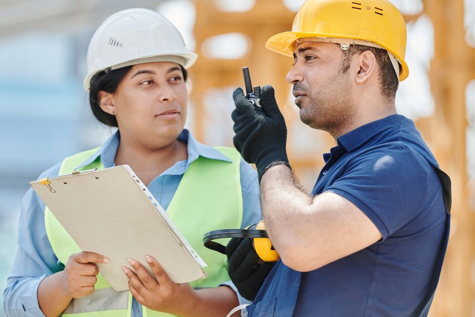 Profissionais de construção civil discutindo planejamento e segurança em uma obra.