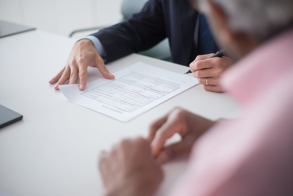 Imagem de uma reunião empresarial onde duas pessoas analisam um documento importante relacionado a negócios ou finanças.