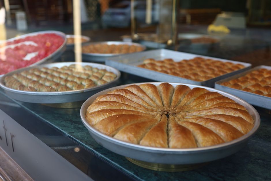 Vitrine exibe uma variedade de salgados e doces tradicionais em uma padaria ou confeitaria ao fundo, com foco na diversidade de opções de alimentos.
