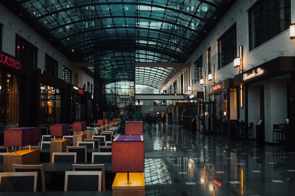 Imagem de um shopping aconchegante e moderninho, com um teto de vidro, iluminação suave e espaço agradável para passear ou fazer compras.