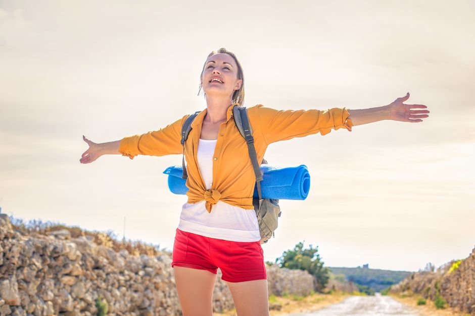 Mulher com mochila ao ar livre, representando liberdade, aventura e conexão com a natureza.