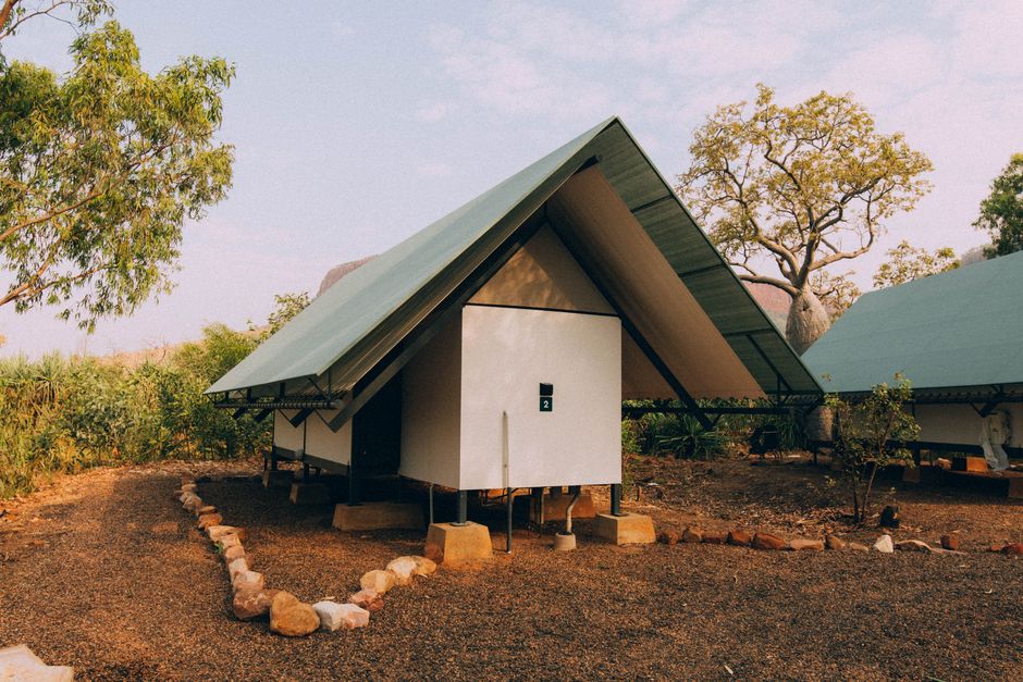 Imagem de uma cabana moderna em meio à natureza, com estrutura triangular e telhado inclinado.