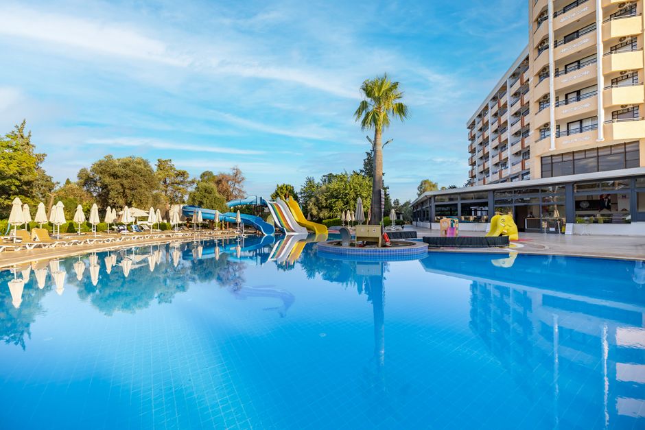 Foto de uma piscina de hotel com áreas de lazer e prédio residencial ao fundo, ideal para artigos sobre turismo, destinos de lazer ou férias corporativas.