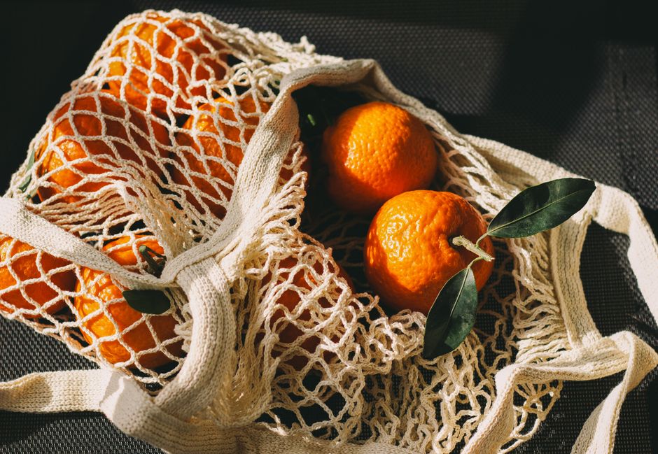 Imagem de uma sacola de algodão com várias tangerinas, destacando o tema de alimentação saudável e consumo de frutas naturais.