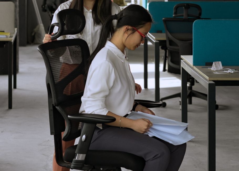 Mulher trabalhando concentrada em um ambiente de escritório, revisando documentos e usando óculos de leitura.