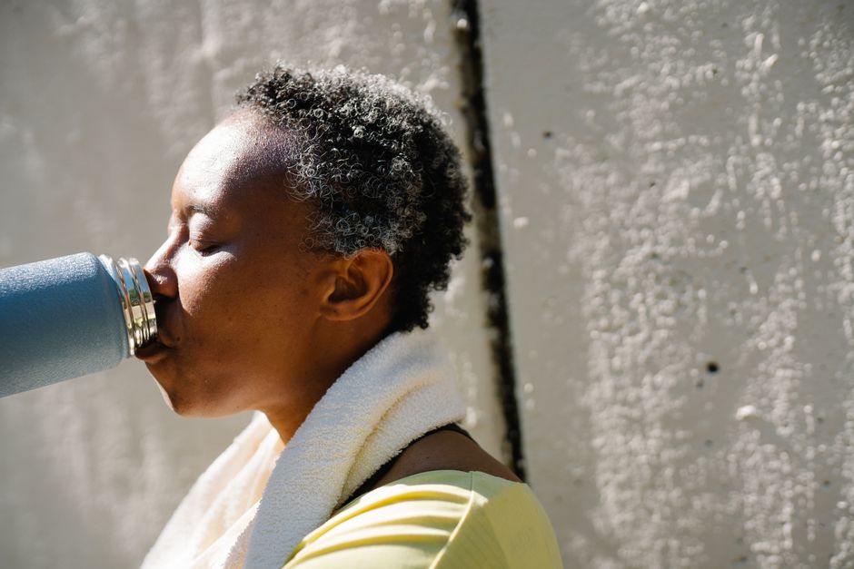 Mulher descansando ao sol após atividade física, com foco na importância do bem-estar e recuperação.