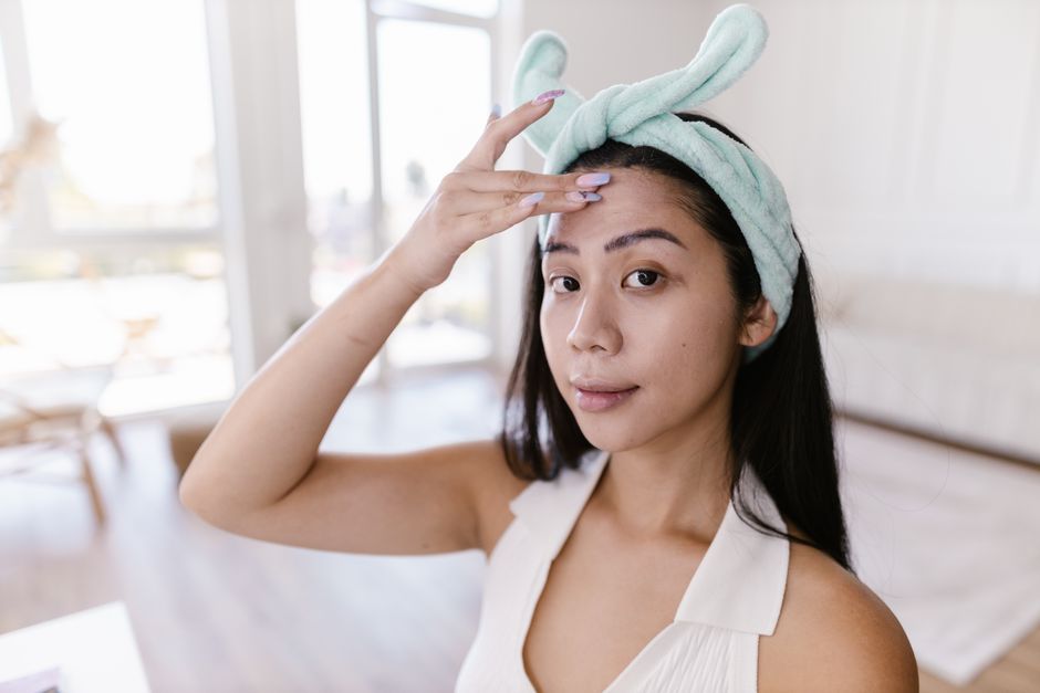 Mulher retirando o excesso de suor da testa após despertar, em ambiente doméstico, representando cuidado com a autocuidado e rotina matinal.