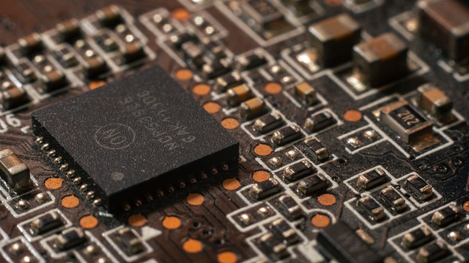 Imagem de um microchip eletrônico em um circuito impresso, destacando a tecnologia e componentes digitais.