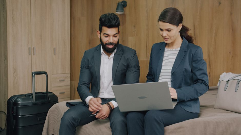 Dois profissionais em uma reunião de negócios, focados em uma apresentação ou discussão, em um ambiente de trabalho corporativo.
