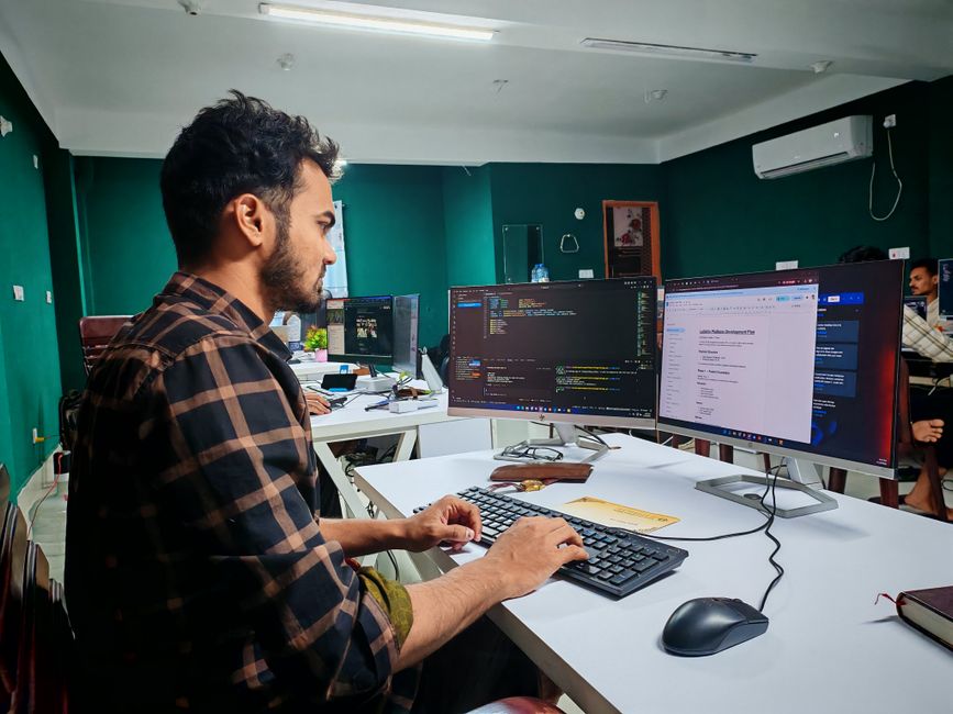 Desenvolvedor de software trabalhando em computadores com foco em programação e tecnologia em um ambiente de escritório moderno.