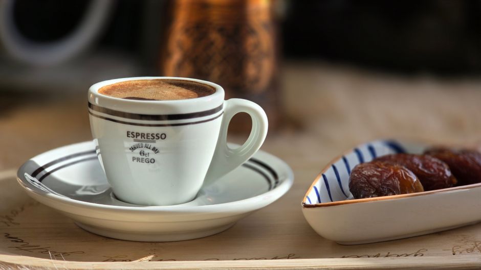 Imagem de uma xícara de café expresso acompanhada de tâmaras, ideal para ilustrar um momento de pausa ou rotina matinal em um blog de bem-estar ou lifestyle.