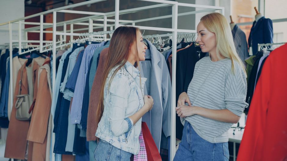 Duas mulheres conversando em uma loja de roupas, ilustrando uma experiência de atendimento ao cliente ou consultoria de moda.