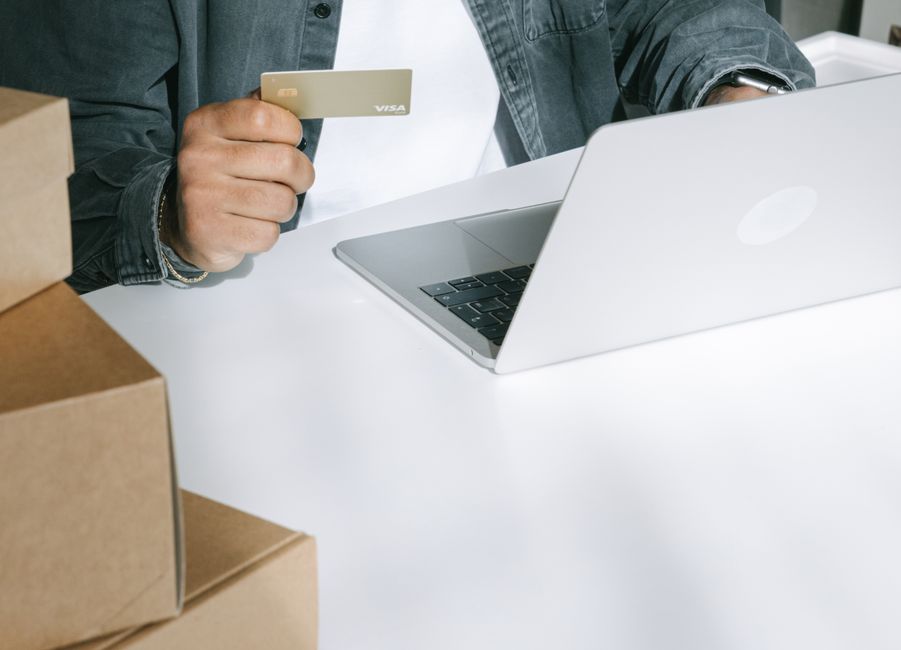 Pessoa realizando uma compra online usando cartão de crédito, com ambiente de trabalho organizado.