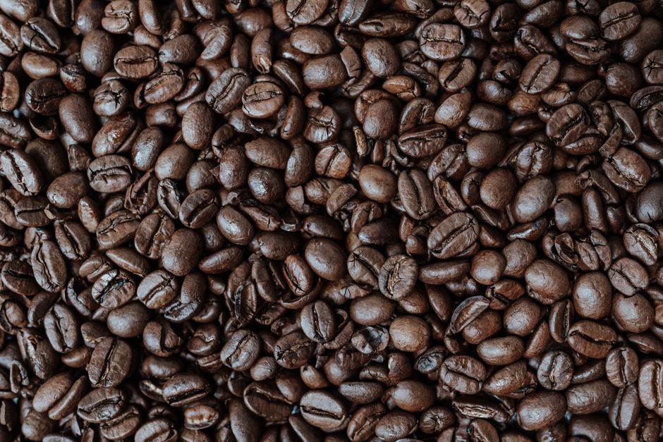 Imagem de grãos de café torrados, destacando sua textura e cor para ilustração de temas relacionados à produção e consumo de café.