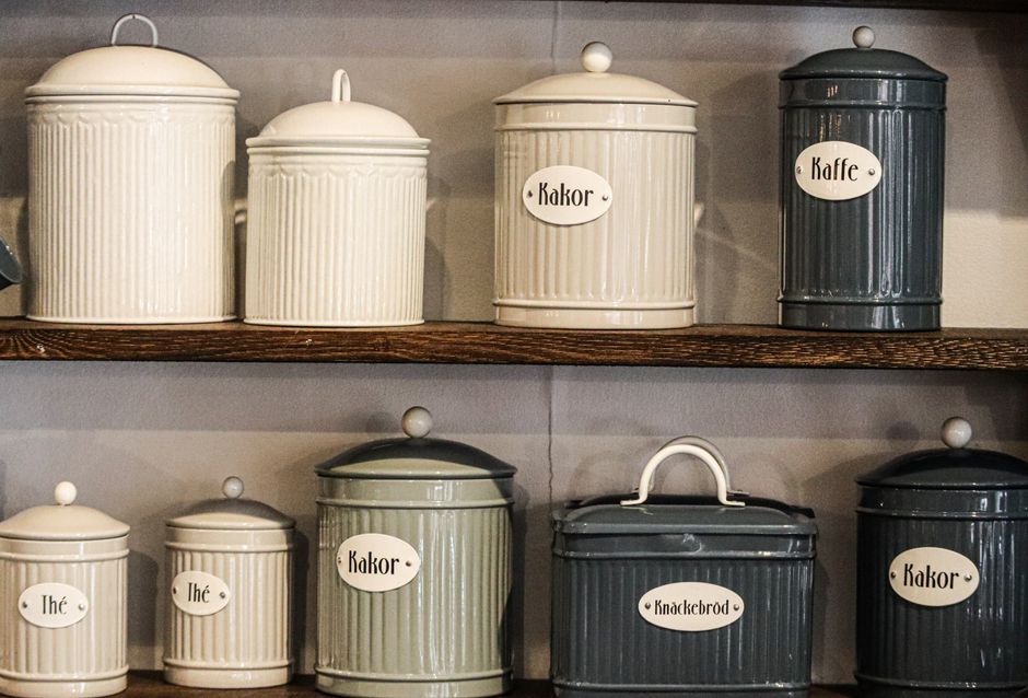 Imagem de potes de vidro vintage usados para armazenamento de café, chá e especiarias, organizados em prateleiras de uma cozinha aconchegante.