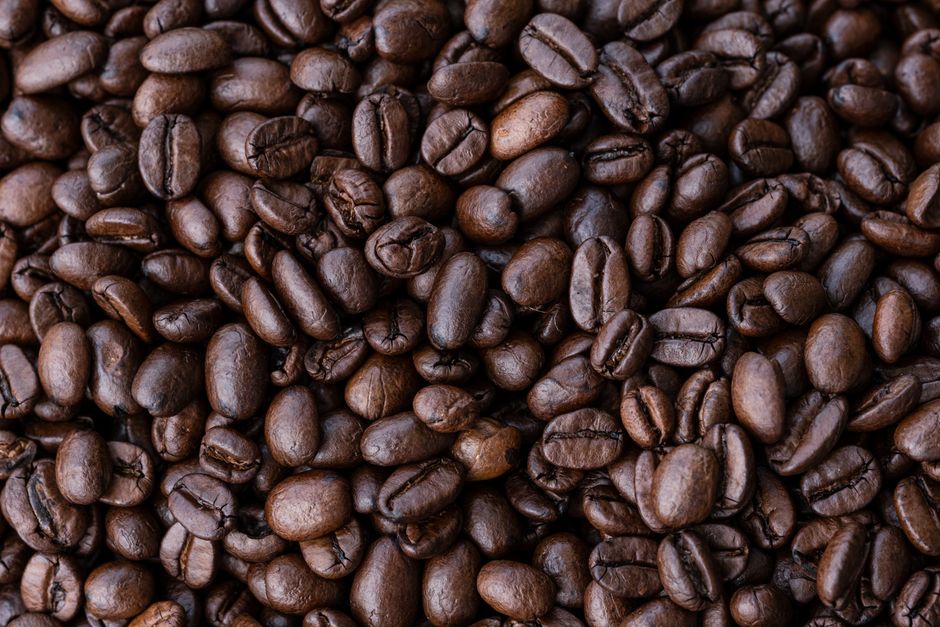 Imagem de grãos de café torrados, destacando sua textura e coloração em tons de marrom.