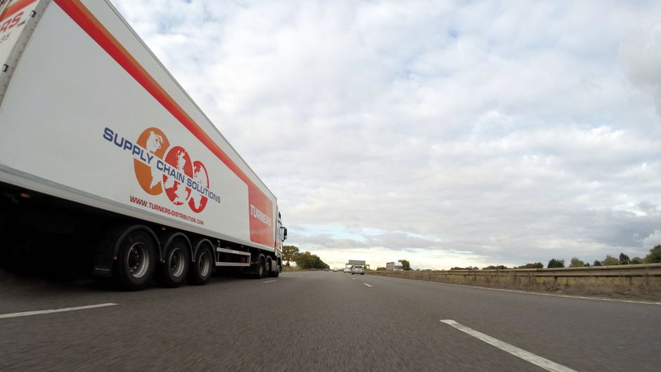 Imagem de uma rodovia com um caminhão de transporte de cargas, simbolizando logística e gestão da cadeia de suprimentos.