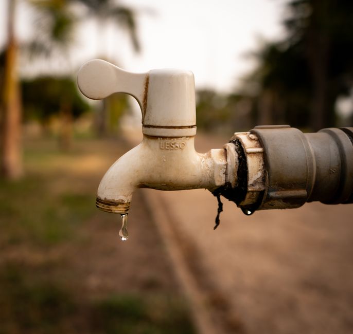 Imagem de uma torneira velha com água escorrendo, simbolizando recursos ou problemas de manutenção em um contexto ambiental ou urbano.