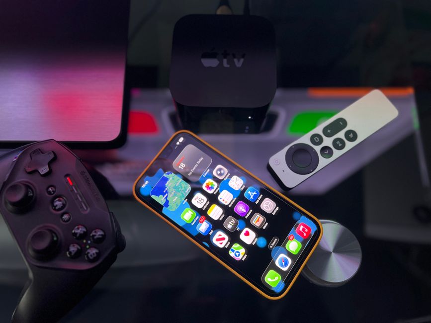 Imagem de uma estação de entretenimento com dispositivos tecnológicos modernos, incluindo smartphone, controle remoto e assistente de streaming, em um ambiente de lazer ou trabalho em casa.
